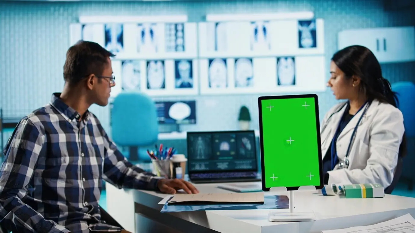 Индийская женщина-медик консультирует пациента рядом с изолированным экраном планшета.